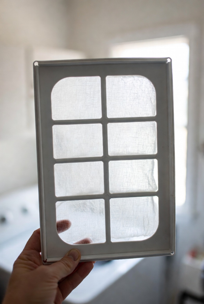 Filtre de sécheuse tenu à contre-jour, propre après entretien